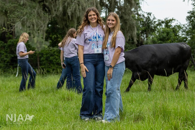 NJAA participants standing in a pasture beside Angus cattle.