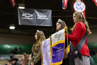 Three Angus queens showcasing the winning banner to onlookers.