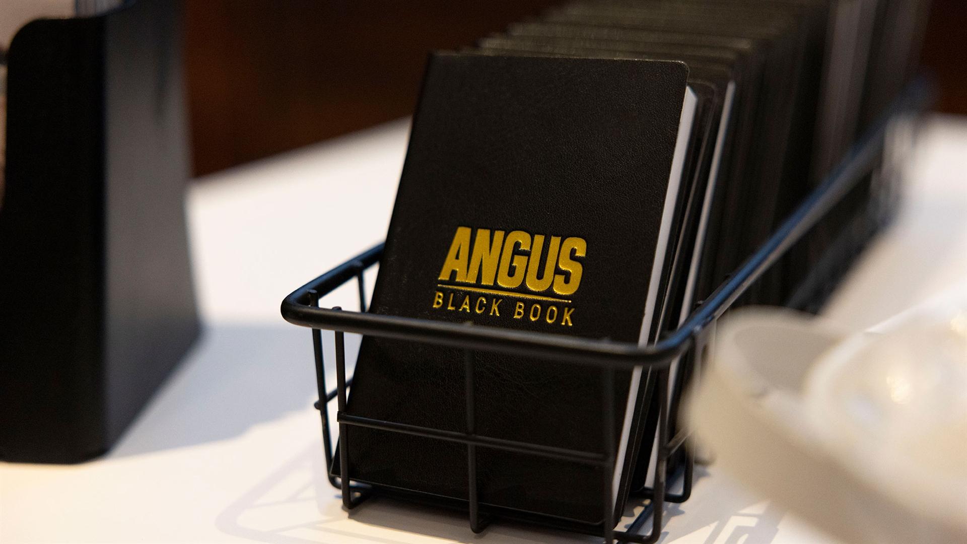 A stack of Angus black books is displayed on a table.