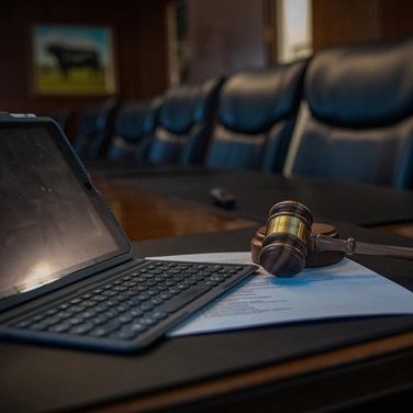Image of a tablet and gavel sitting on a table in a board room.