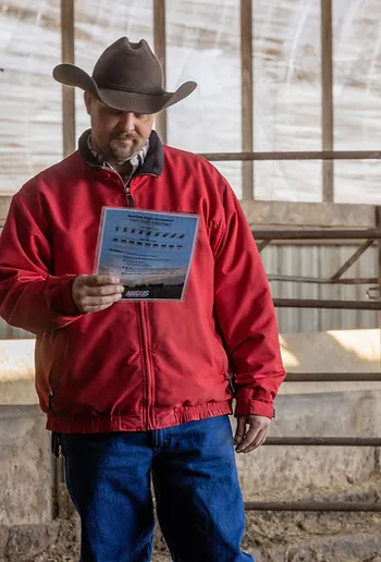 Man in red coat and cowboy hat looking at a flyer