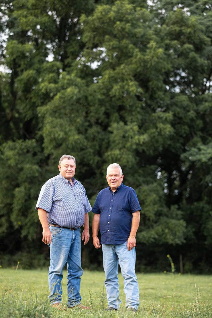 Two men stand in a field 