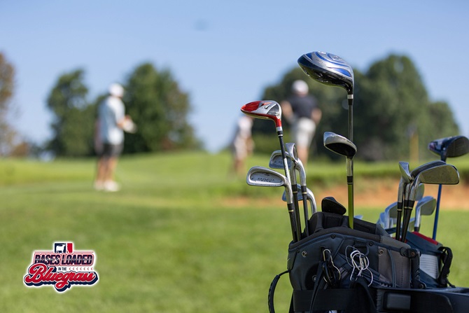 Golf clubs stand ready beside the fairway as participants make their way up the course during the Bases Loaded in the Bluegrass golf tournament.