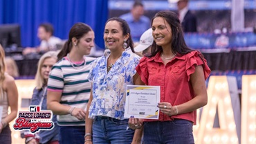 An award presenter stands with an NJAA scholarship recipient at the 2026 National Junior Angus Show.
