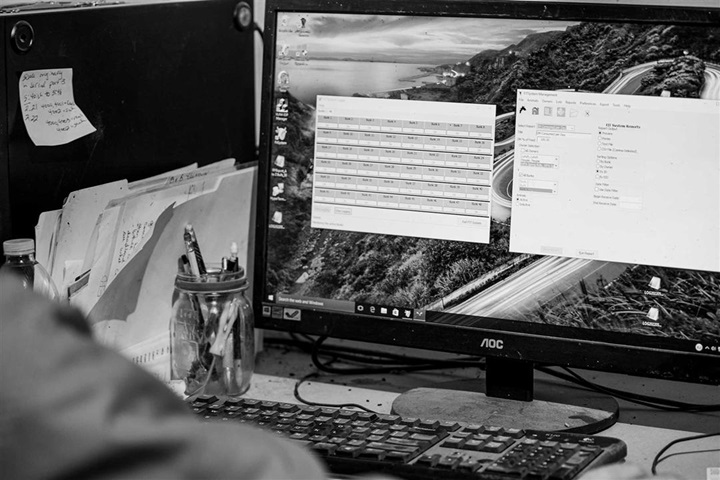 Black and white photo of an individual entering data on the computer.