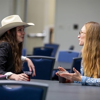 Two young cattlewomen having a discussion at a conference table.
