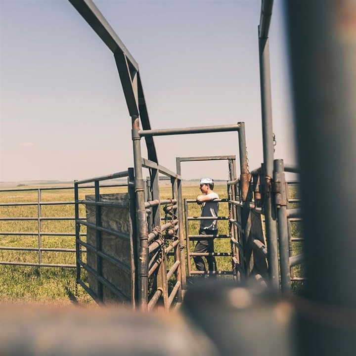 Cowboy standing at the end of an alleyway gate opening.