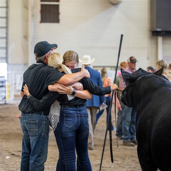 A female exhibitor giving a hug to her dad and sister after exiting the showring.