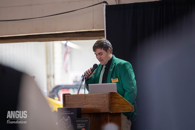 A member of the NJAA Junior Board stands at the podium introducing the items available for auction at the Angus Foundation Herdsman Social.