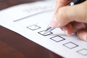 A person's hand crossing off a checklist on a piece of paper.