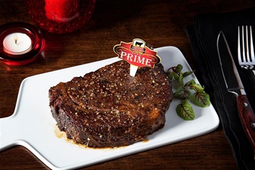 A Certified Angus Beef prime steak plated on a restaurant table. 