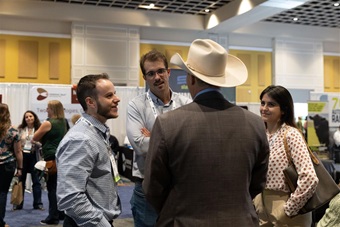 Three gentlemen and woman having conversation at a trade show