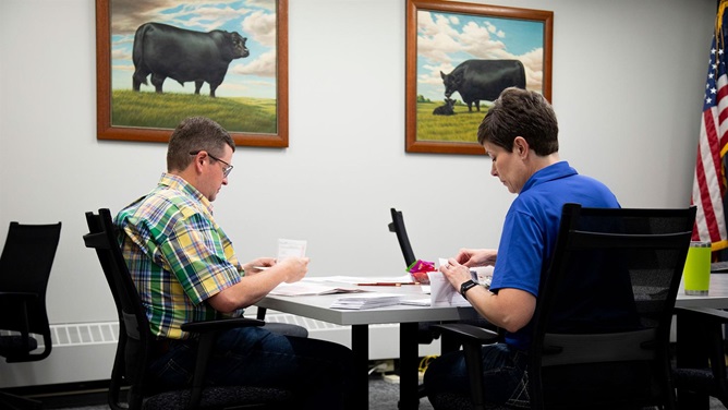 A man and woman sit in an office at American Angus Association headquarters to count paper ballots submitted by members to elect delegates for the 143rd Annual Convention of Delegates.