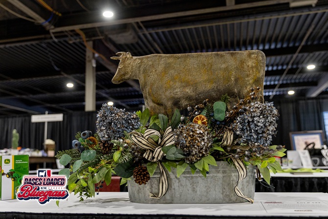 Rustic floral centerpiece with a metal cattle silhouette arranged as a silent auction item.