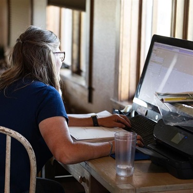 A woman entering herd data at a home computer.
