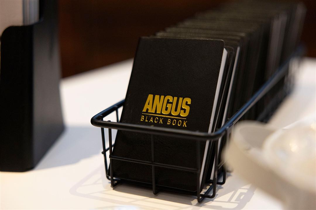 A stack of Angus black books is displayed on a table.