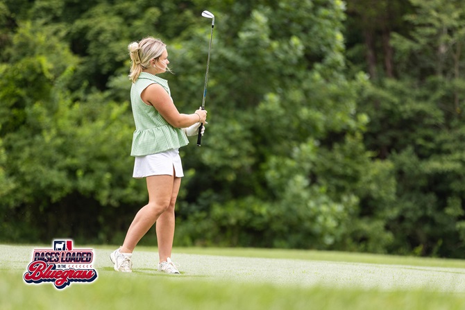 A golfer watches the flight of a shot from the fairway during tournament competition.