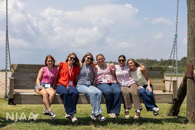 NJAA participants sitting together on a large wooden swing.