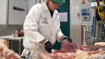 A meat cutter at The Producer Partnership processes donated beef into a retail cut that will be donated to a local food bank. 