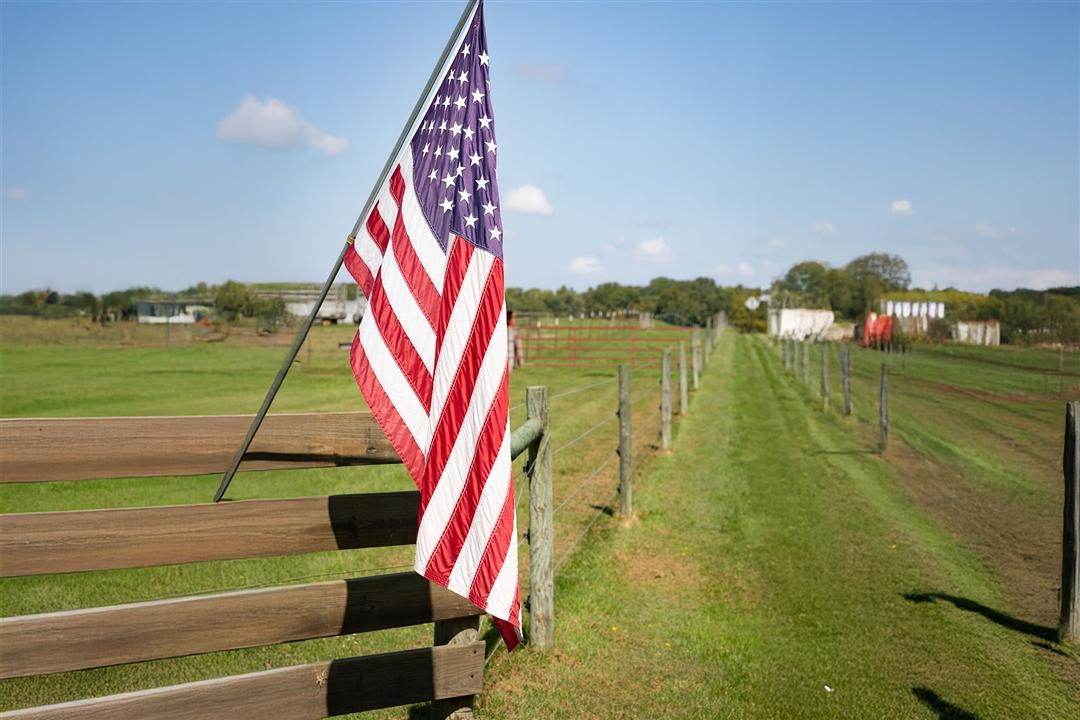 An American flag on a pasture fenceline.
