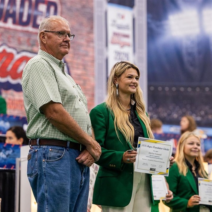 Angus Foundation scholarship recipient poses with a supporter while holding a scholarship certificate during the scholarship presentations at the National Junior Angus Show.