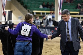 A livestock judge shaking the hand of an winning exhibitor.