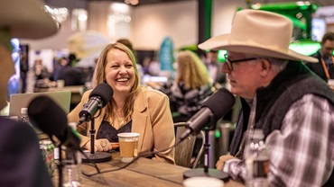 Man in a cowboy hat and a women speaking into podcast microphones at a convention.