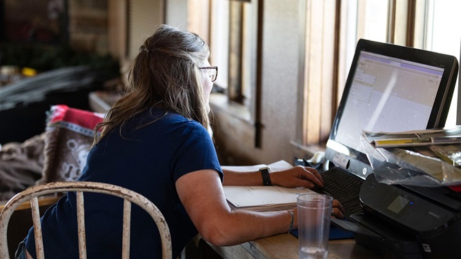 A woman entering herd data at a home computer.