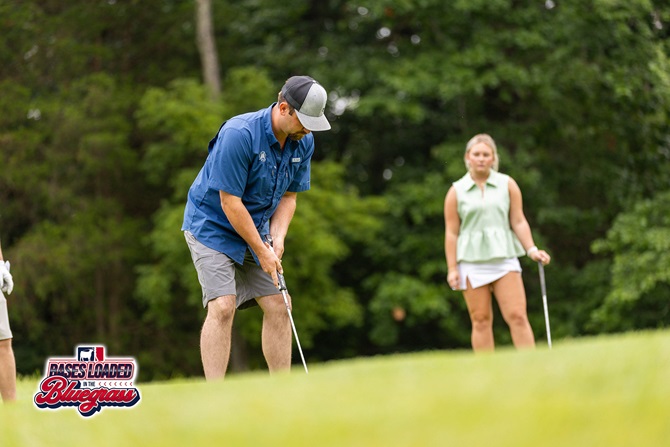 A participant chips toward the green as fellow golfers look on.