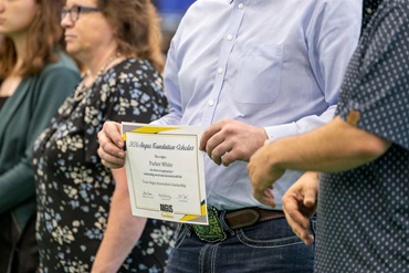 Close-up of an Angus Foundation scholarship certificate held by a scholarship recipient during the recognition ceremony at the National Junior Angus Show.
