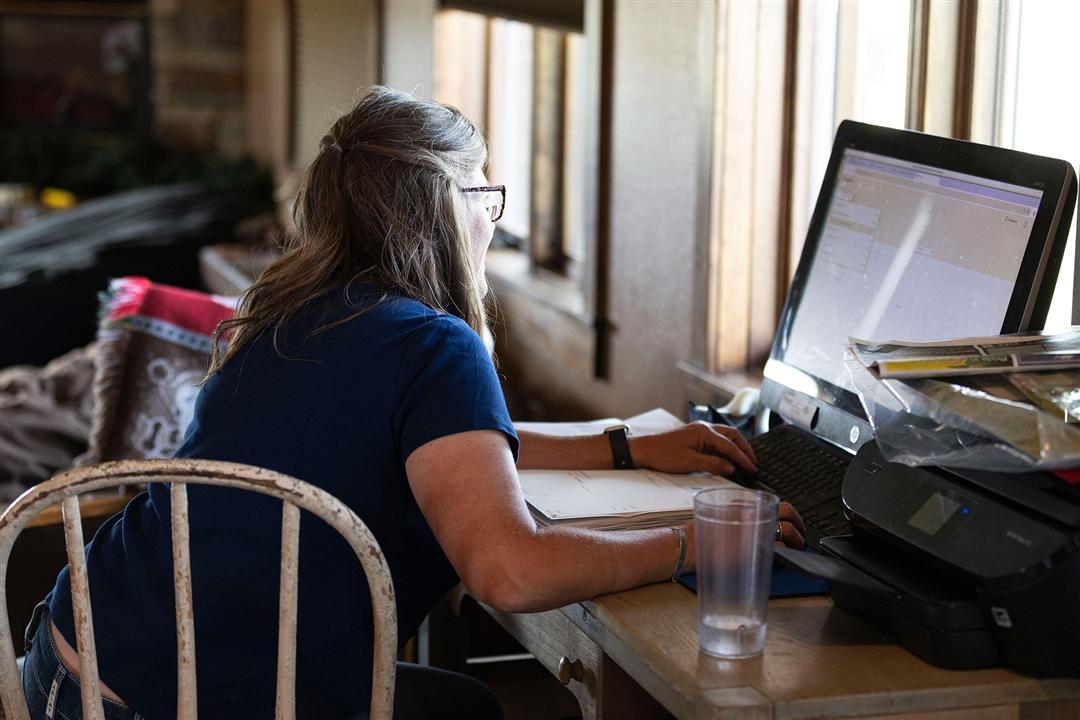 A woman entering herd data at a home computer.