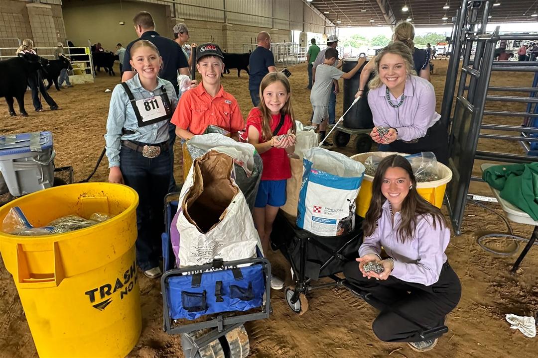 Junior members smile while displaying pop tabs collected for the Angus Impact service project alongside two NJAB representatives.