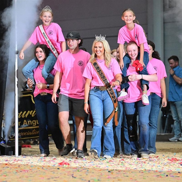 Group of junior members from the same state entering opening ceremonies at National Junior Angus Show in pink shirts.