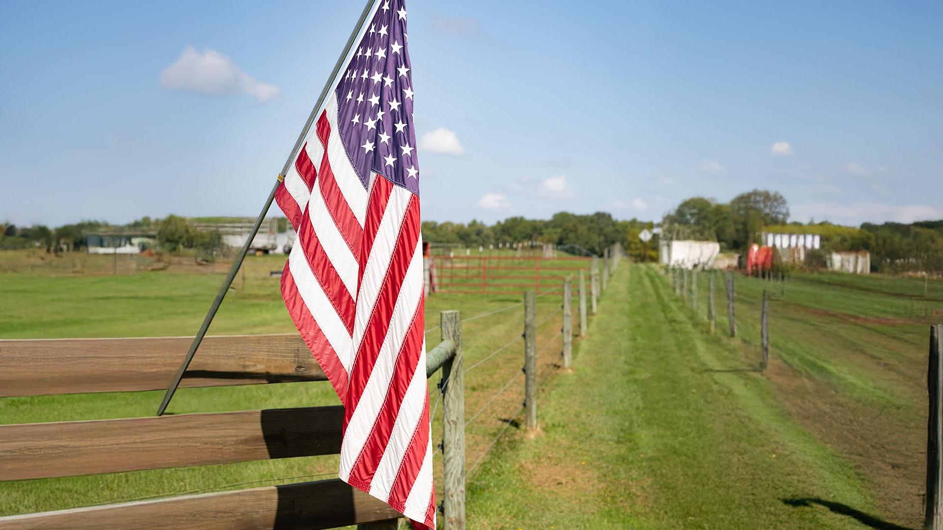 An American flag on a pasture fenceline.