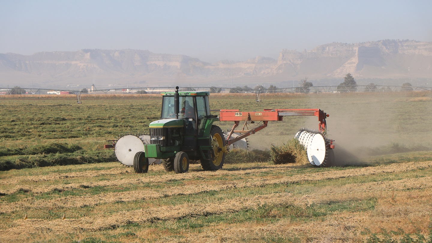 A farmer rakes cut alfalfa, which will be baled east of Scottsbluff, Neb. [Photo by Chabella Guzman.]