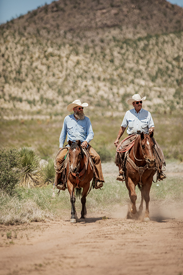 two cowboys riding horses