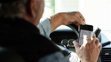 Producer examining data on phone while parked in vehicle