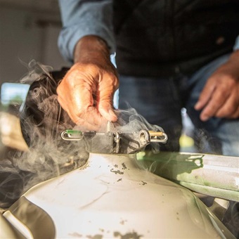 Individual pulling a semen straw out of a semen tank full of nitrogen