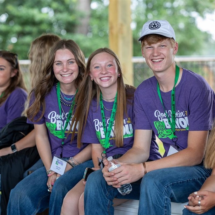 A group of NJAA members sitting on a bench in purple shirts and smiling at the camera.