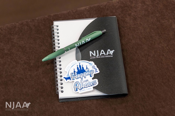 NJAA LEAD notebook, pen, and event sticker on a table.
