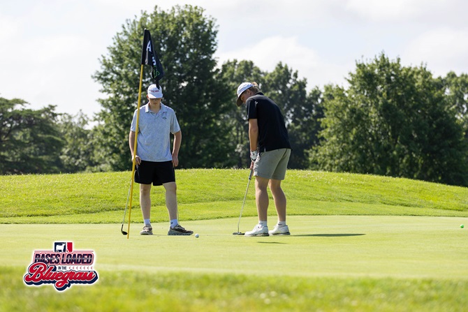 Two golfers line up a putt on the green during competition at the Bases Loaded in the Bluegrass golf tournament.