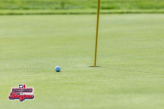 A golf ball comes to rest near the cup during tournament play.