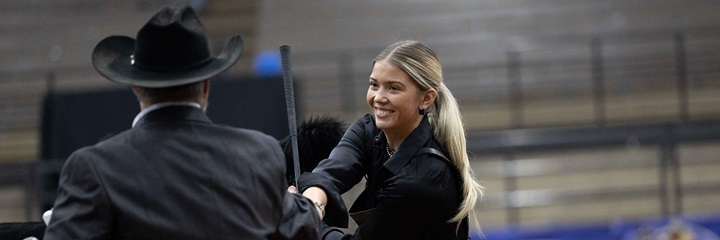 A young female showman shakes hands with the judge in the exhibitor ring.