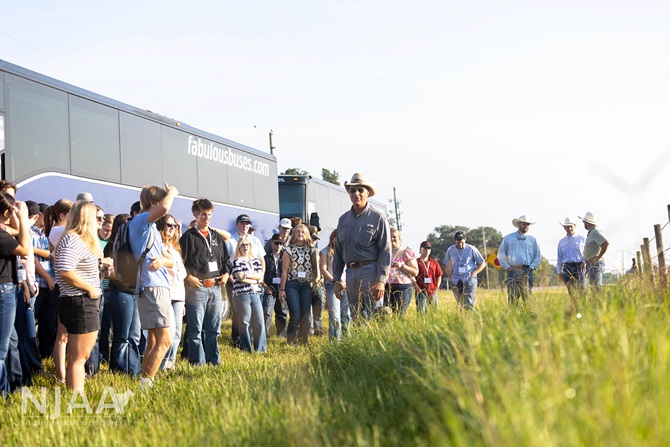 NJAA participants gathering for a ranch tour near tour buses.