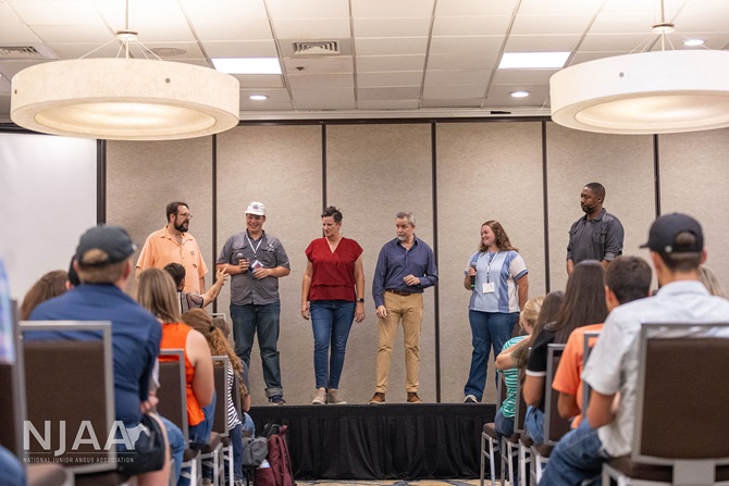 Facilitators leading an on-stage activity before a seated audience.