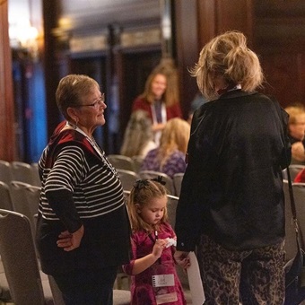 Two women and a young girl speak to one another during the Auxiliary annual meeting.
