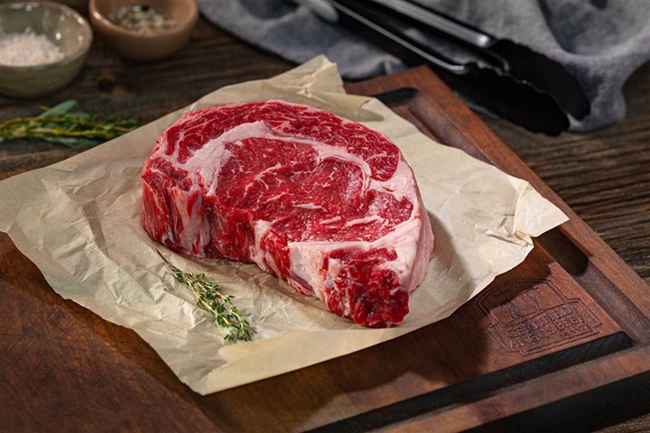 A prime graded ribeye laying on a piece of butcher paper.