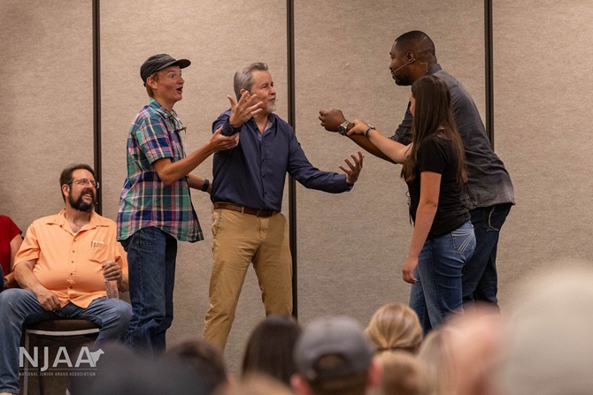 Presenters and participants interacting on stage during a workshop.