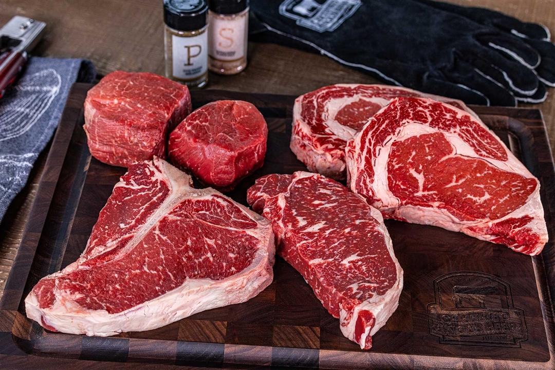 A variety of prime retail meat cuts displayed on a cutting board, ready for food preparation.