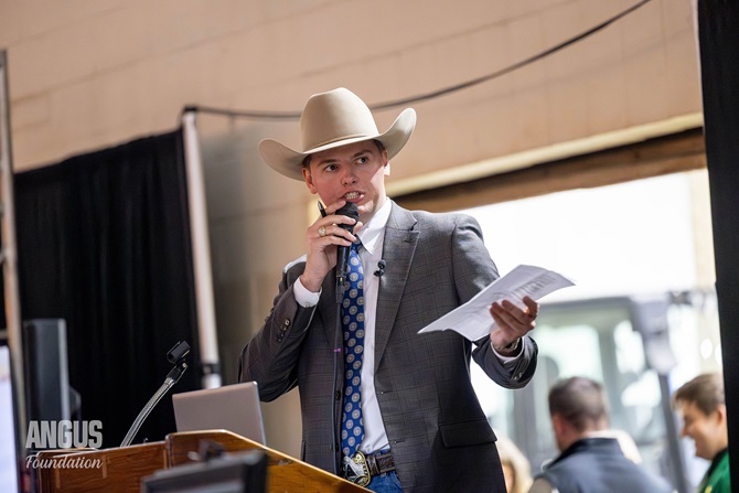 A man in a cowboy hat stands at the podium introducing the items available for auction at the Angus Foundation Herdsman Social.